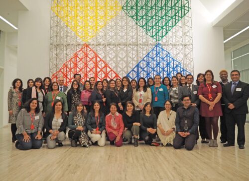 A group of people with formal/semiformal clothes posing on the first floor at Aga Khan Centre