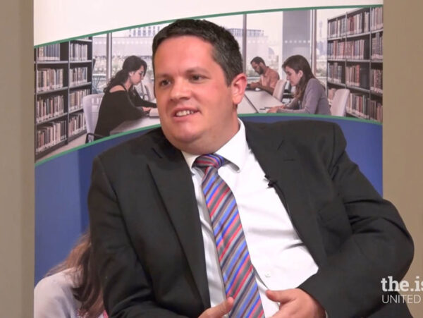 An image from the.ismaili United Kingdom with Dr. Stephen Burge sitting on a couch and talking and some students working in the background