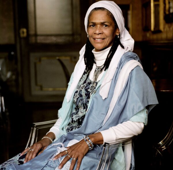 An image of Amina wadud sitting on a chair and posing