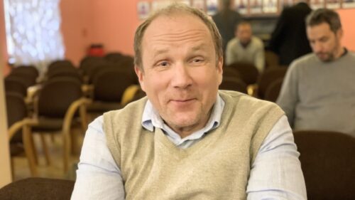 Dr Janis Esots, an esteemed scholar in white shirt and light yellow sweater