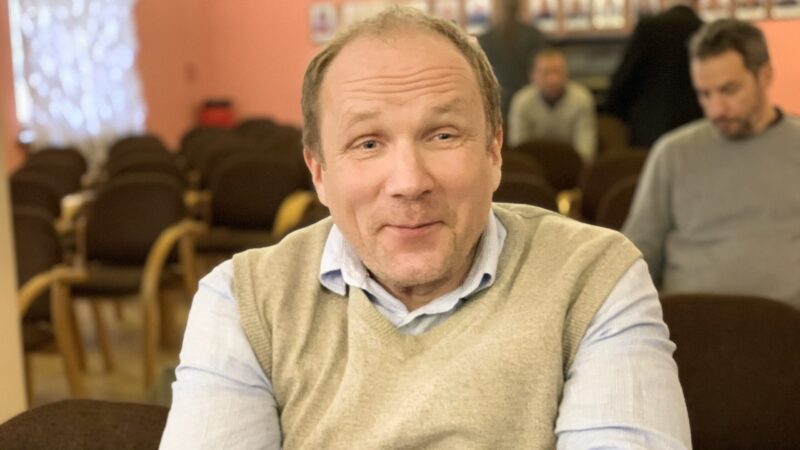 Dr Janis Esots, an esteemed scholar in white shirt and light yellow sweater