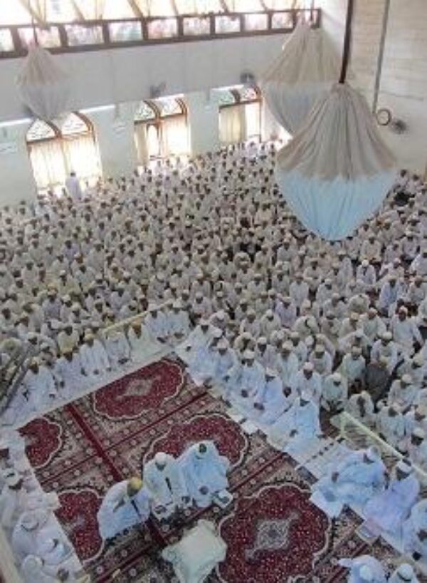 A huge crowd of people gathered in a place of worship and praying together