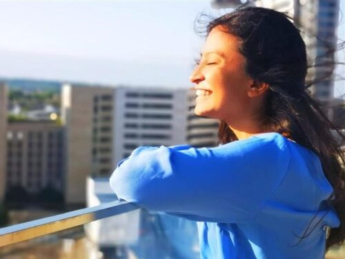 A girl in sky blue hoody smiling and looking away