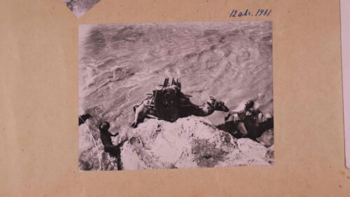 A Camel walking in a desert with people on its back (image from a coin)