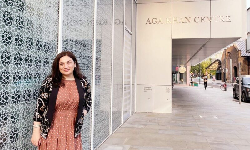 STEP student Fariza Sheralieva in a peach dress and black cardigan standing outside of Aga Khan Centre and posing for a picture