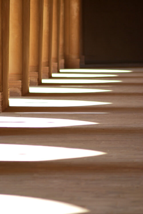 A line of pillars and their shadows falling on the ground