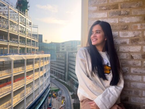 An IIS student dressed in white looking at a distant view and posing from the kitchen balcony of Victoria Hall