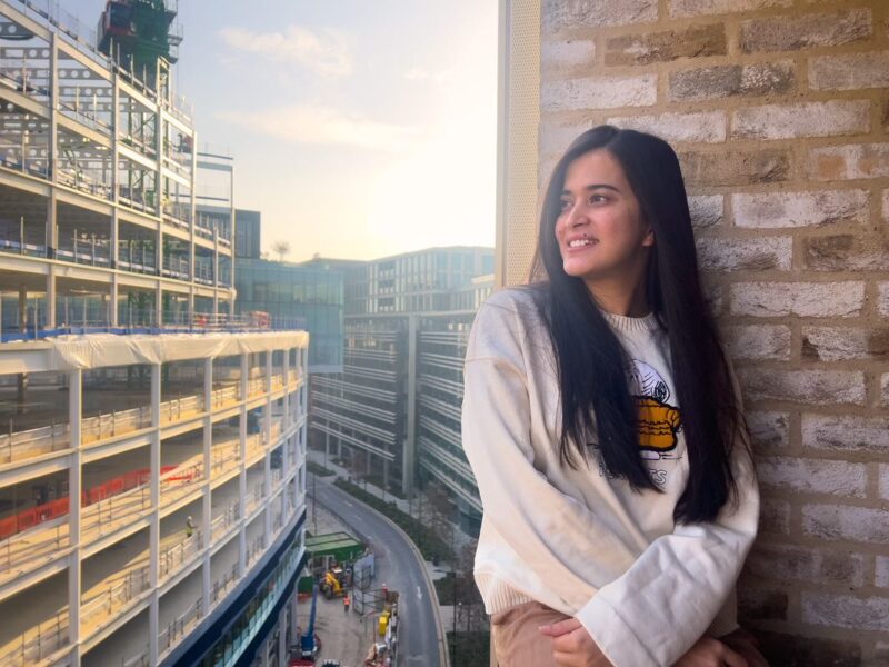 An IIS student dressed in white looking at a distant view and posing from the kitchen balcony of Victoria Hall