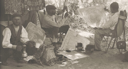 Some men working in a forest ground analysing an enlarged piece of document that looks like a circular design