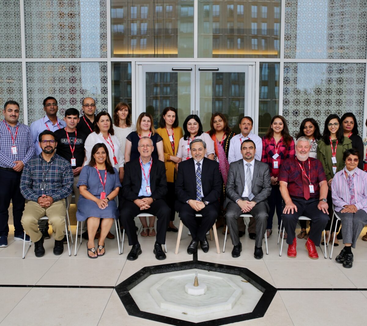 Teacher Educator Graduates with their faculties posing for a group photo with red ID cards around their neck on the first floor of Aga Khan Centre (AKC)