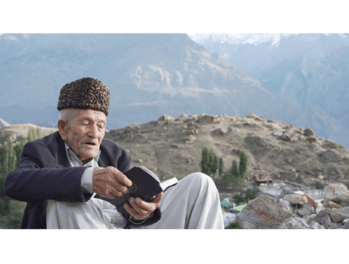 a man in a rural Pakistan reading from his notes for IIS Oral History Project.