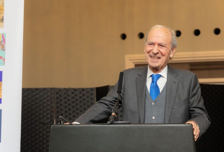 Dr Farhad Daftary in a business suit standing at a lectern, delivering a speech at an event.