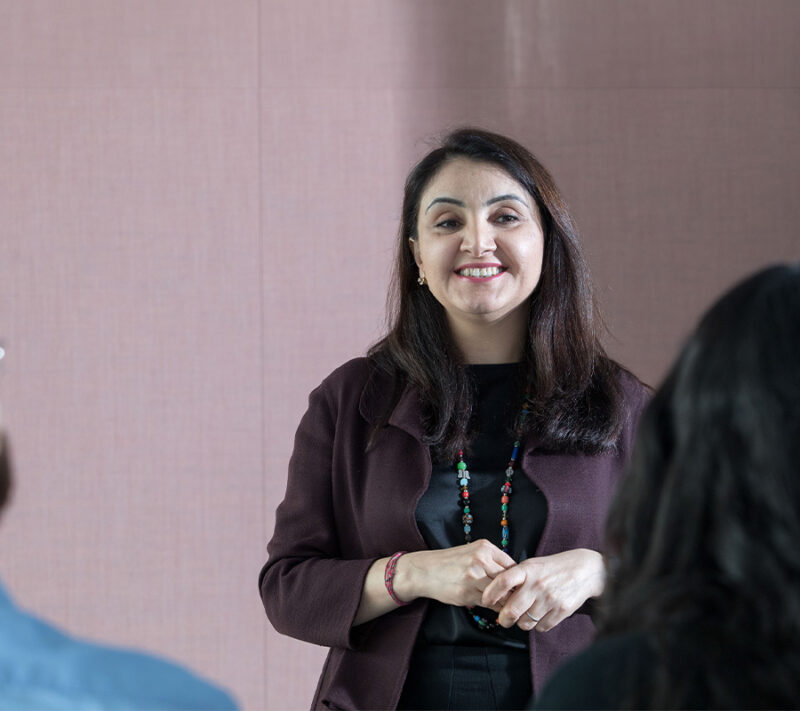 A woman confidently addressing a group of people, commanding attention and engaging in public speaking.