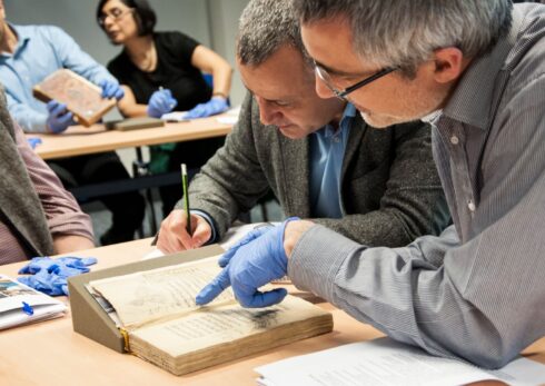 Two scholars working on a manuscript with gloves