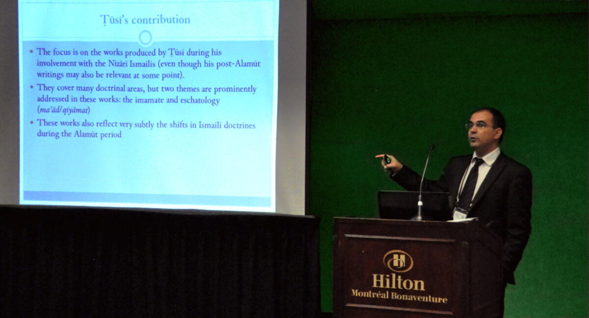 A man in a suit presenting something on a projector