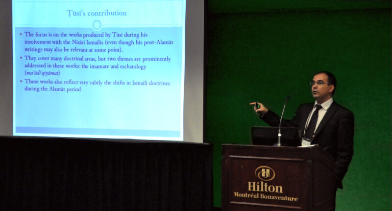 A man in a suit presenting something on a projector