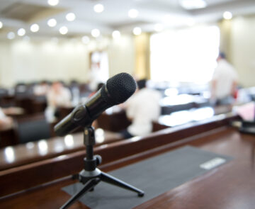 A black microphone lying on a podium with a blurry background