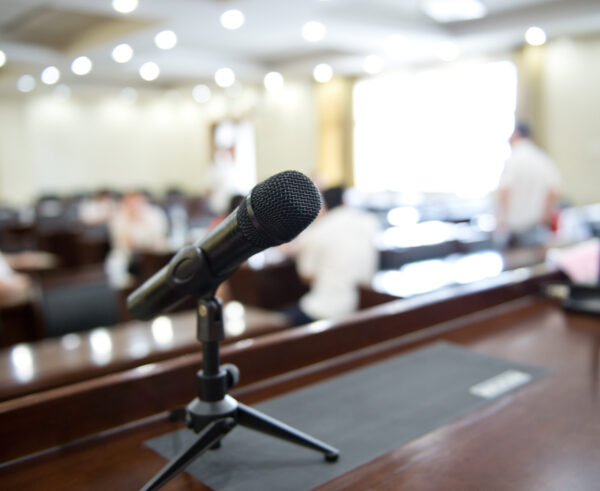 A black microphone lying on a podium with a blurry background