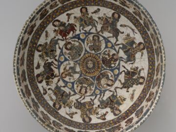A round dish with diverse colour combinations and humans, animals and geometric designs painted inside of it