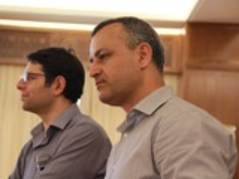 Two men (sideview) standing and looking at something