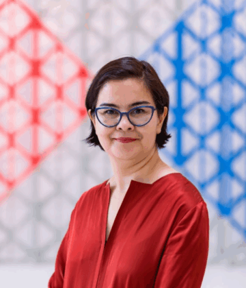 Marjan Afsharian in a red shirt posing for a photo with a AKC background