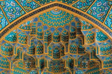 An image of a ceiling from an architectural building with sections of blue shaded tiles and golden border around them