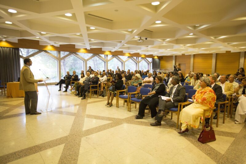 A man addressing a big group of people in a room