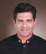 Riaz Rhemtulla in a formal black shirt posing for a photo