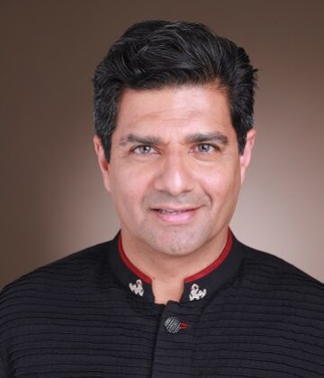 Riaz Rhemtulla in a formal black shirt posing for a photo